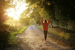 woman in recovery from addiction walking on pathway with arms over her head